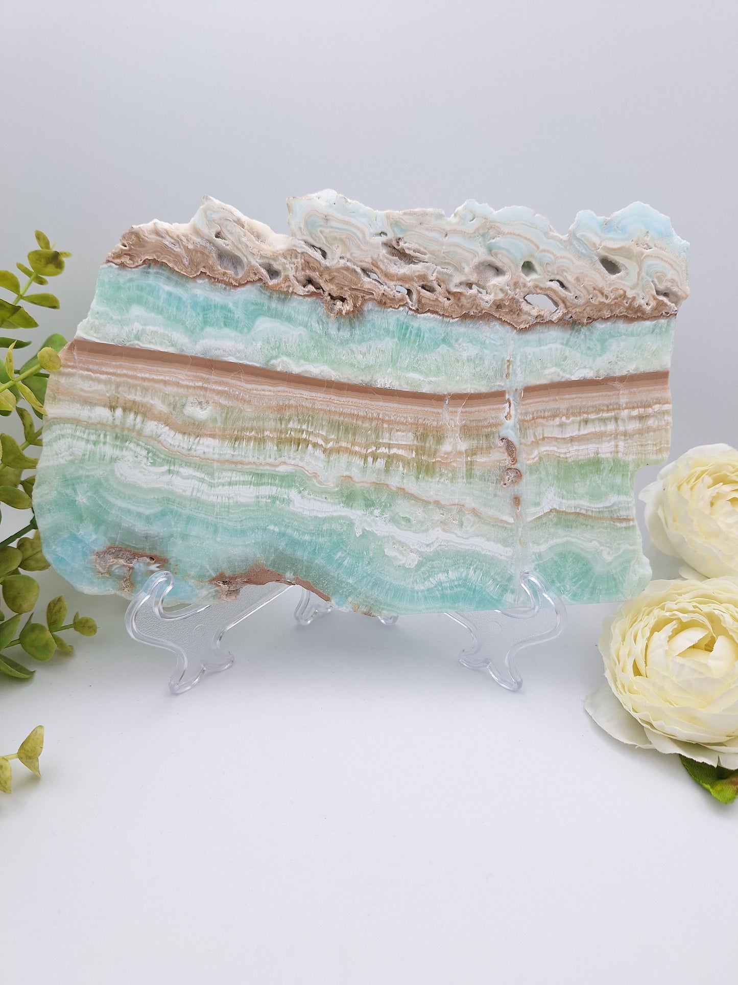 Caribbean Calcite polished slab displayed on a stand, showcasing its soft blue, white, and beige tones with natural patterns.