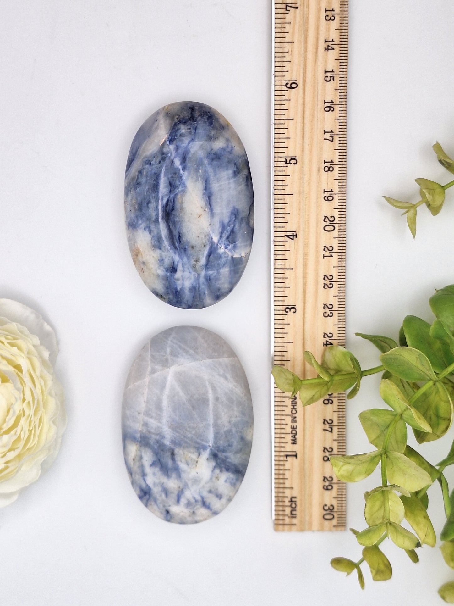 Polished Afghanite palm stone placed next to a ruler for size reference. This blue and white mineral, related to Sodalite, is prized for its rarity and connection to higher energies.