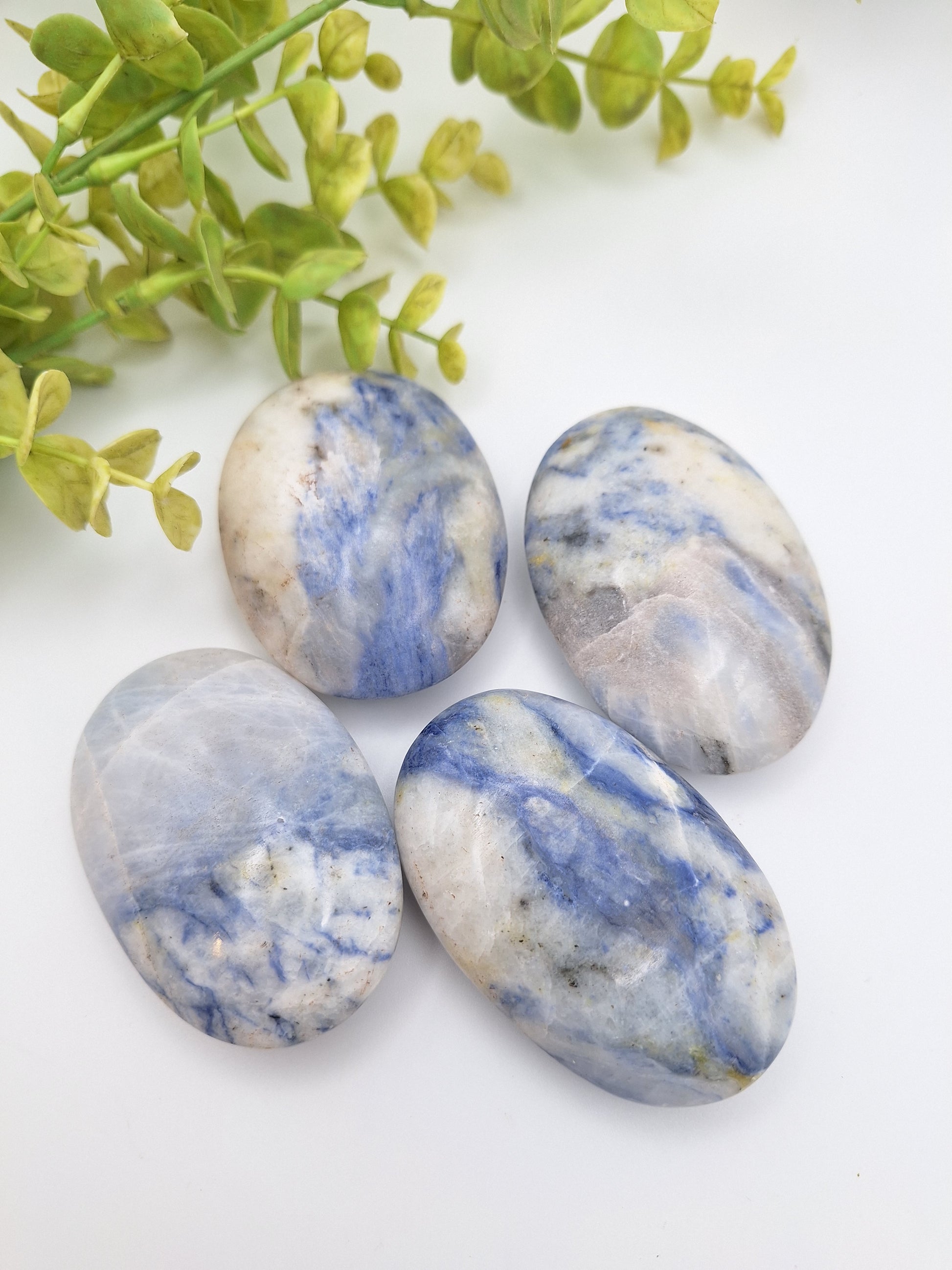 A collection of polished Afghanite palm stones with vibrant blue and white patterns. A rare mineral related to Sodalite, valued for both its geological beauty and metaphysical properties