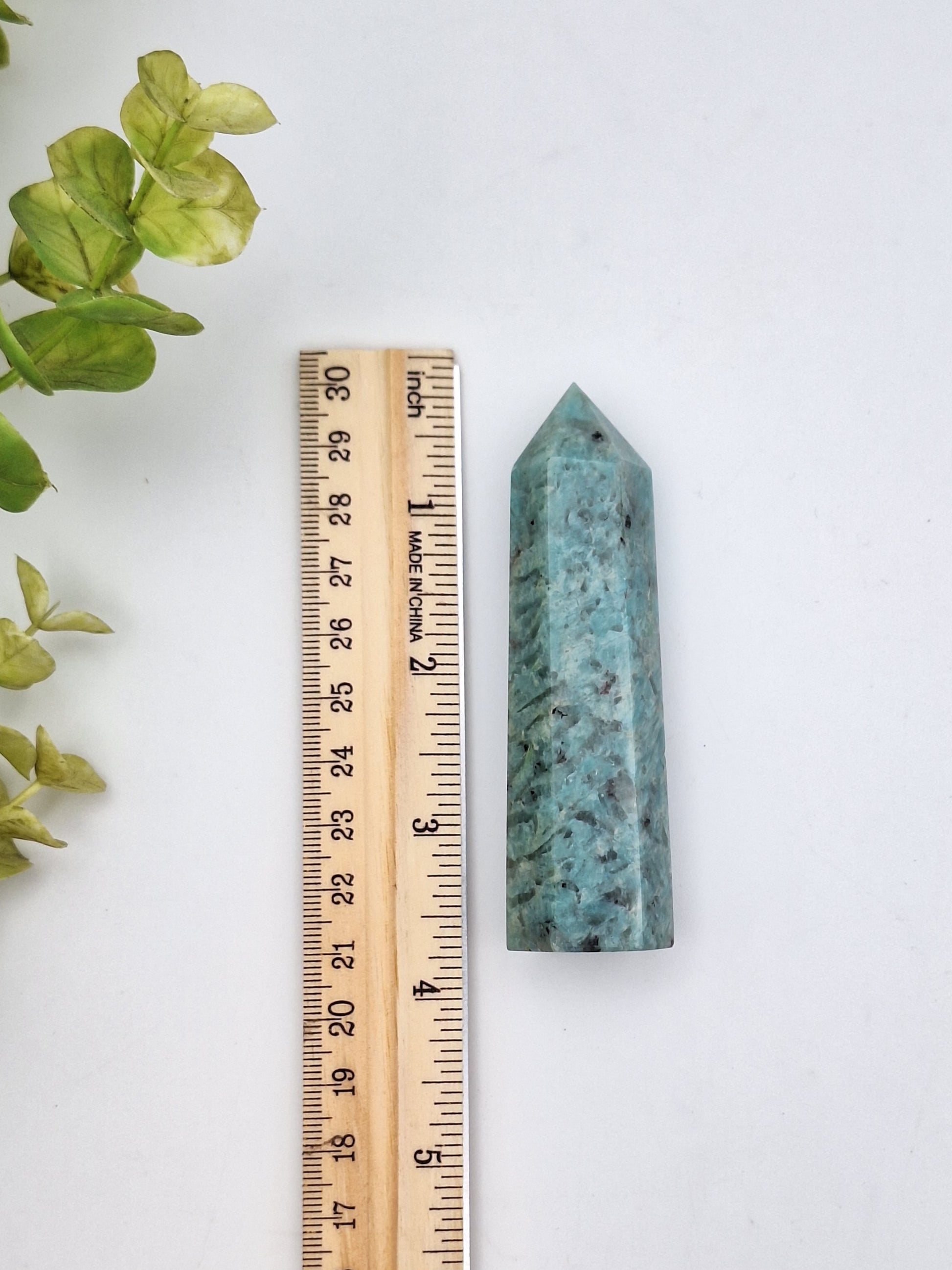 An Amazonite tower point placed next to a ruler for size reference, showcasing its polished surface and calming energy.