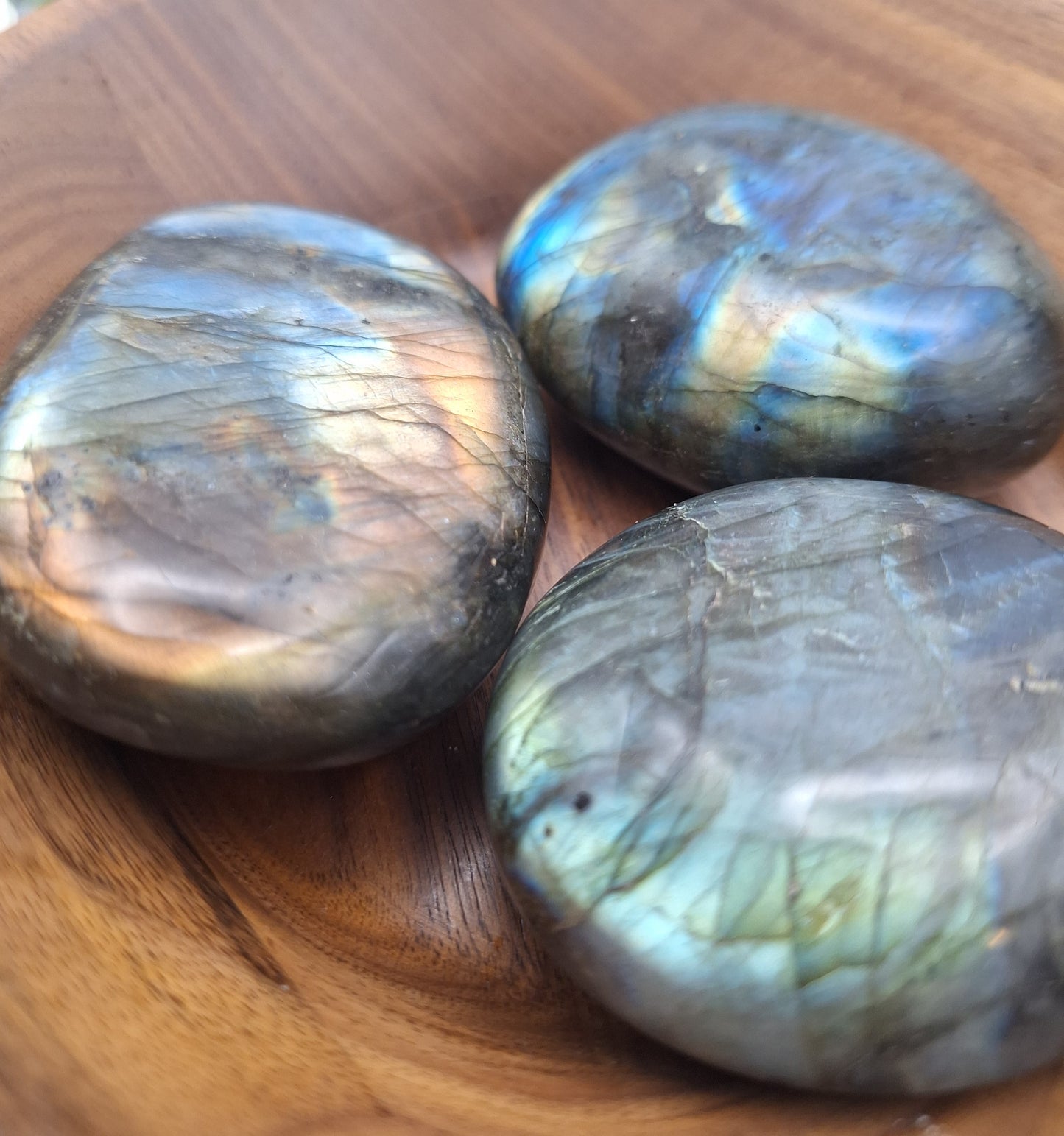 Close-up of three polished Labradorite palm stones from Madagascar, displaying smooth surfaces with hints of natural flash.