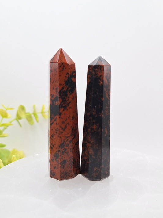 Two polished Mahogany Obsidian tower points standing upright, showcasing their deep black and reddish-brown natural patterns.