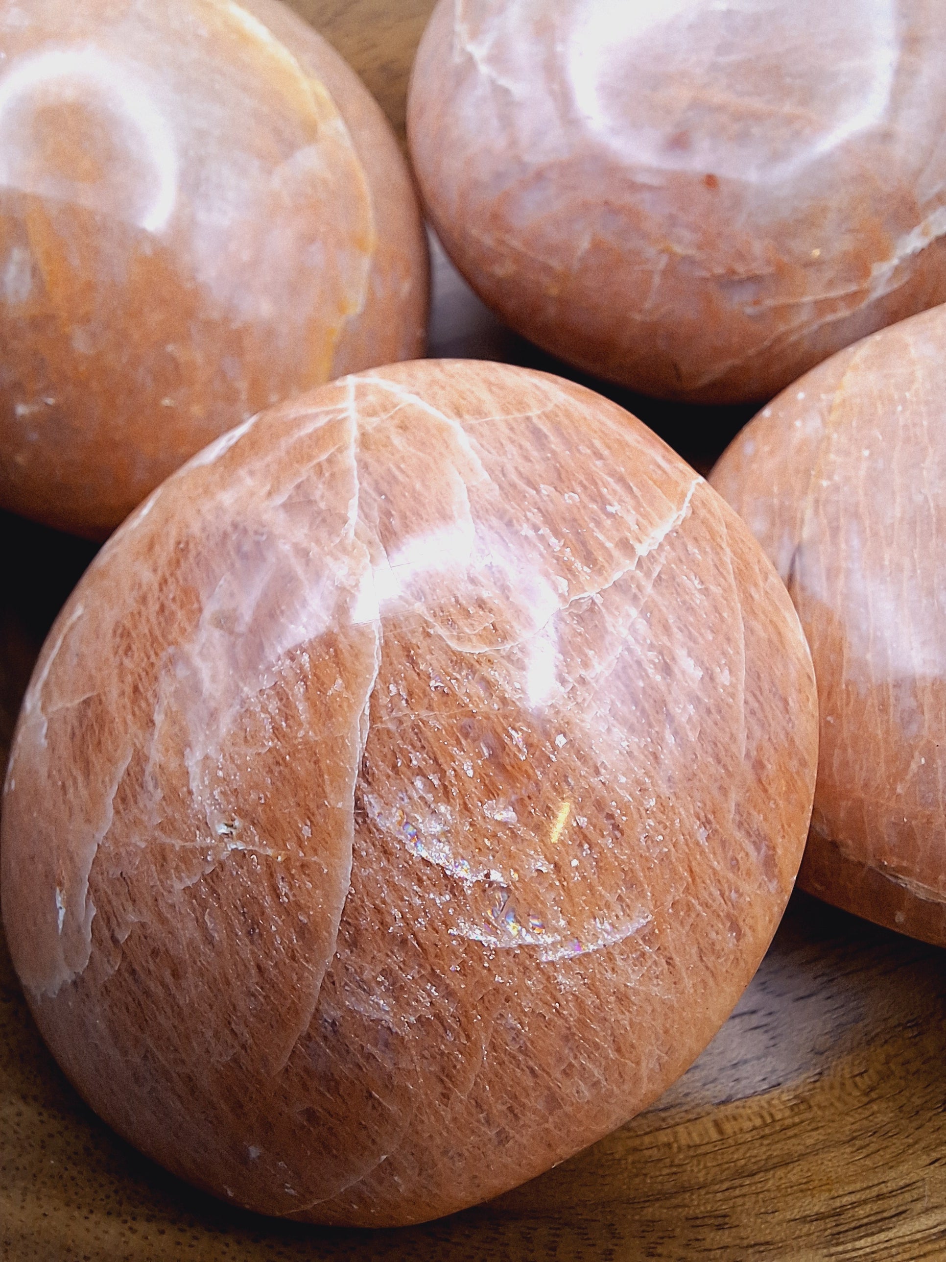 Close-up view of Peach Moonstone palm stones, highlighting their soft peach coloration, polished surface, and natural shimmer.