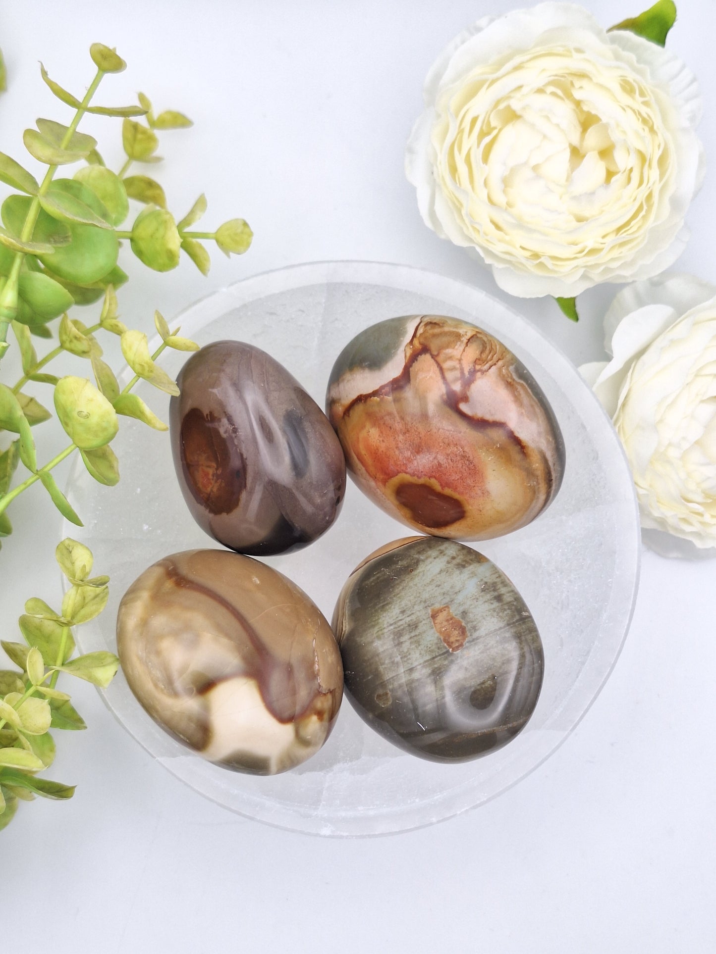 A collection of Polychrome Jasper palm stones with vibrant swirls of red, orange, and brown, polished smooth and sourced from Madagascar.