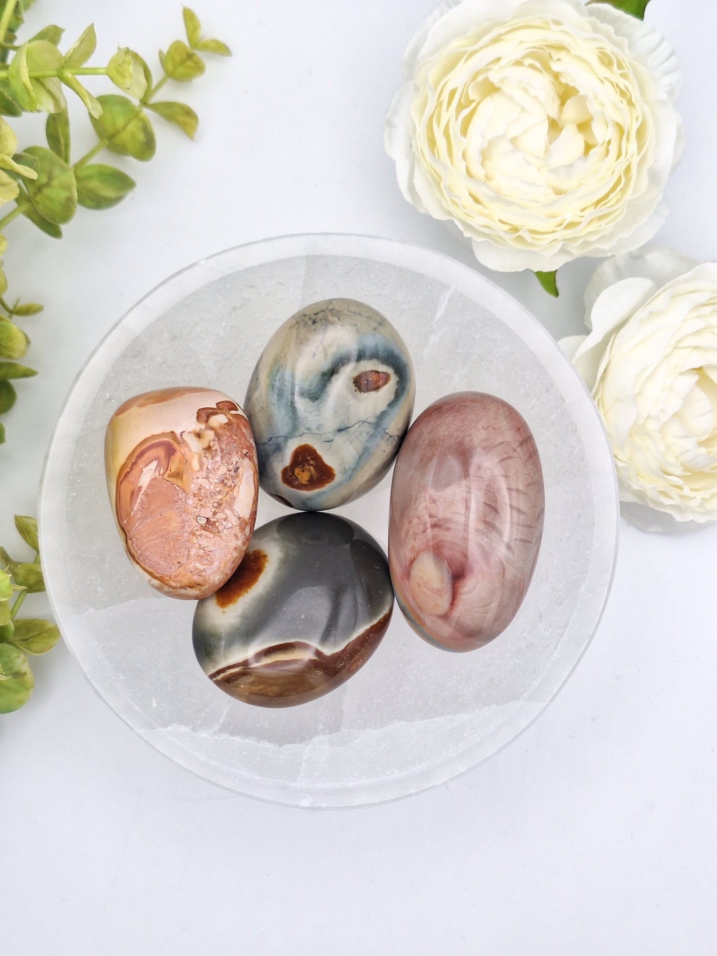 group of Polychrome Jasper palm stones showcasing their rich, multicolored patterns and highly polished surfaces."