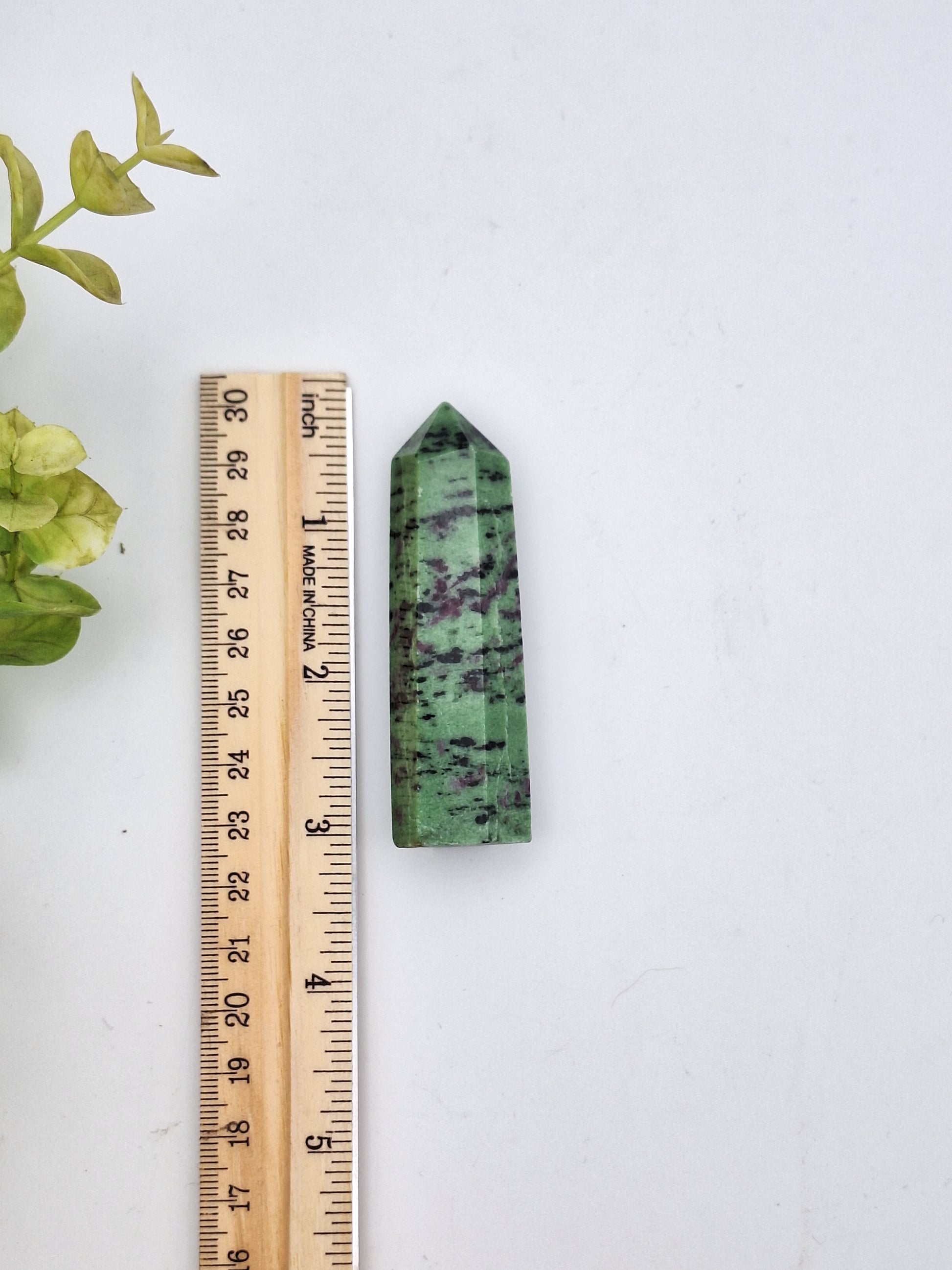 Ruby zoisite tower with a ruler for size reference, showcasing green and pink crystal hues.