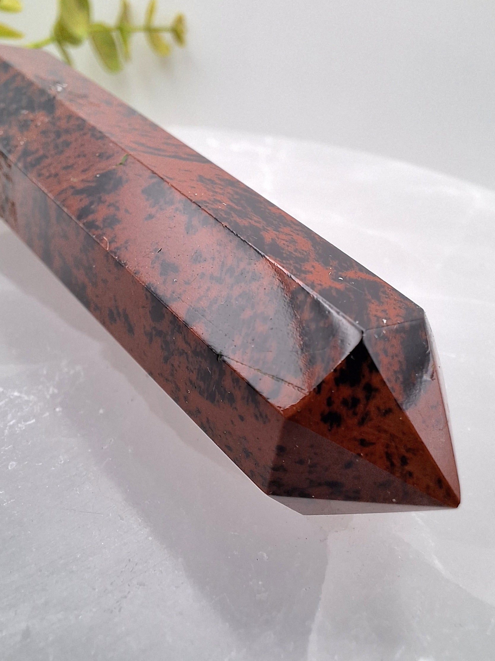 Close-up side view of a Mahogany Obsidian tower point, highlighting its smooth polish and rich mahogany streaks.